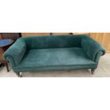 A Victorian Chesterfield settee with a green velour upholstery on turned legs and casters