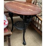 A pub table with a circular top and cast iron base with figure head terminals