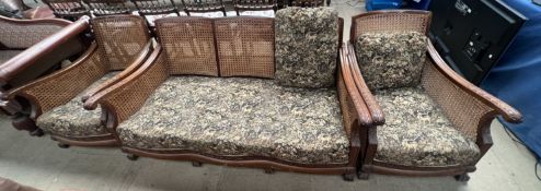 A walnut framed bergere suite comprising a three seater settee and two arm chairs