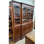 A reproduction mahogany breakfront bookcase with a moulded dentil cornice above four glazed doors