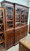 A reproduction mahogany breakfront bookcase with a moulded dentil cornice above four glazed doors
