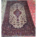 A rug with a central red ground medallion and cream field with multiple guard stripes and overall