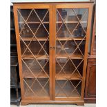 A reproduction mahogany bookcase with a moulded cornice above a pair of glazed doors with glazing