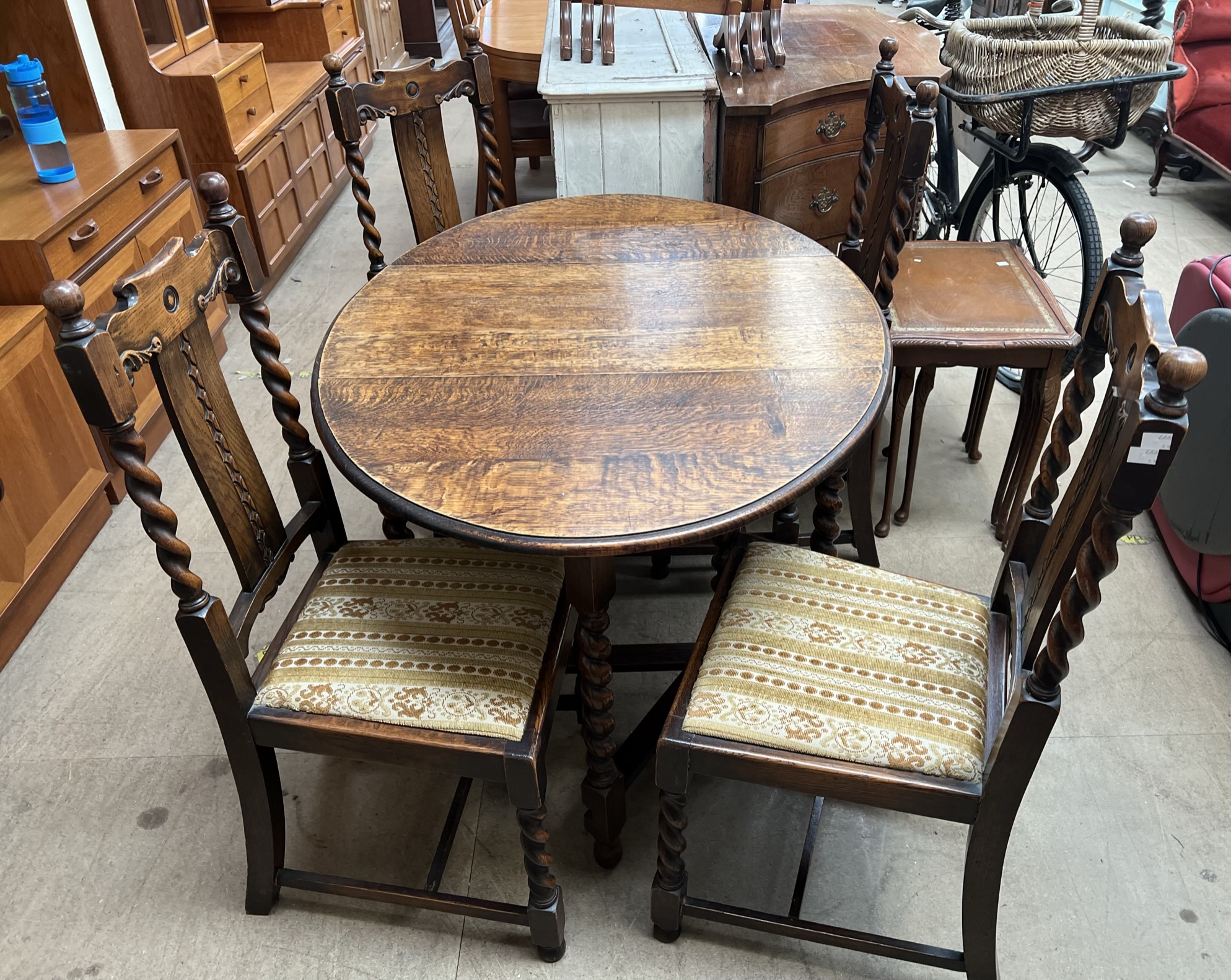 A 20th century oak gateleg dining table on barley twist legs together with a set of four oak dining