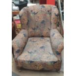 A large Victorian upholstered wing back armchair on turned feet and casters