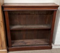 A Victorian walnut bookcase with a moulded cornice above shelves on a plinth,