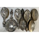 A silver backed part dressing table set comprising a hand mirror and two brushes decorated with