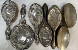 A silver backed part dressing table set comprising a hand mirror and two brushes decorated with