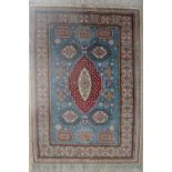 A silk rug with a blue ground and medallions to multiple guard stripes and fringes,