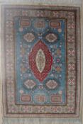 A silk rug with a blue ground and medallions to multiple guard stripes and fringes,