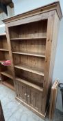 A modern pine bookcase with a moulded top,