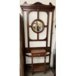 An Edwardian walnut hall stand, with a shaped cornice, circular mirror, drawer and stick stands,