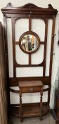 An Edwardian walnut hall stand, with a shaped cornice, circular mirror, drawer and stick stands,