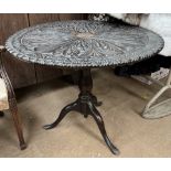 A 19th century ebonised tripod table with a carved circular top on a bird cage action on a baluster