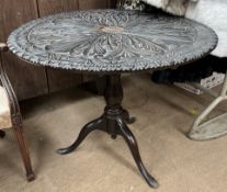 A 19th century ebonised tripod table with a carved circular top on a bird cage action on a baluster