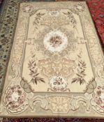 A rug with a cream ground and central floral panel, the edges decorated with flowers and leaves,