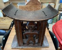 A carved African stool with a dished top with figural supports on a dished rectangular base,