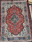 A rug with a central red medallion and interlaced flowers with cream ground spandrels and multiple