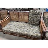 A walnut framed bergere suite comprising a three seater settee and two arm chairs