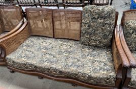 A walnut framed bergere suite comprising a three seater settee and two arm chairs