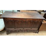 An 18th century oak coffer with a planked rectangular top above a four panelled front and base