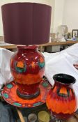 A large Poole pottery table lamp together with a similar charger and vase in reds and oranges