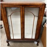 A 20th century walnut display cabinet with a pair of glazed doors on cabriole legs and claw and