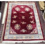 A Chinese rug with a red ground and multiple dragon roundels to a cream and red border,