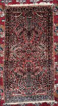 A small red ground rug with vase decorations to multiple guard stripes,