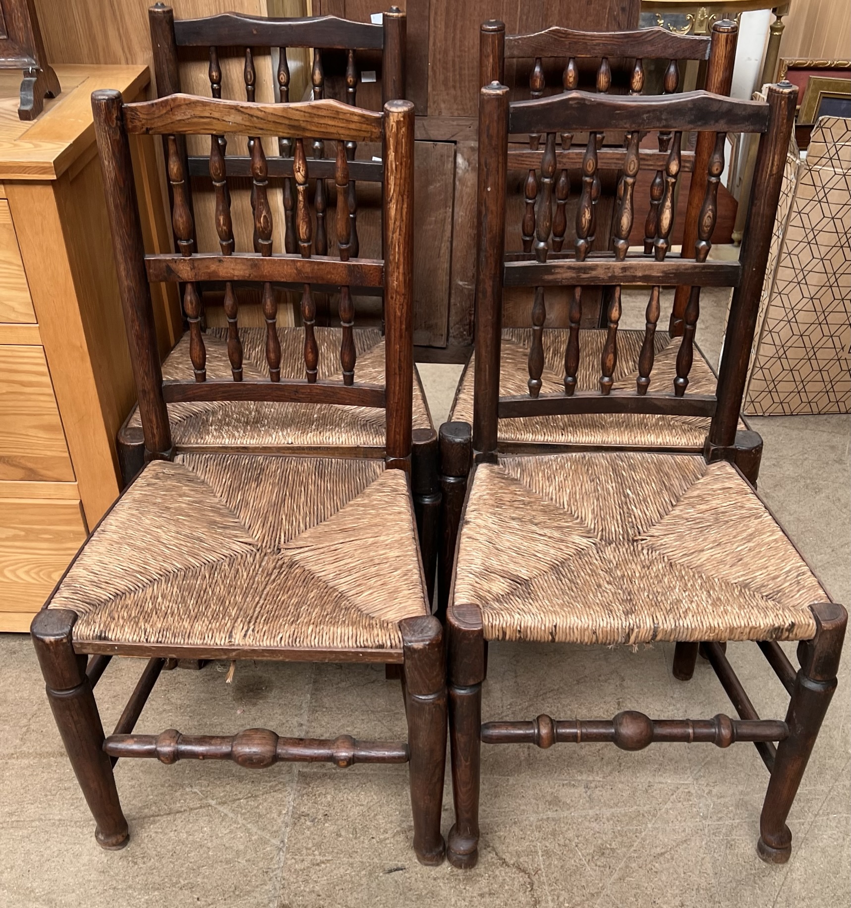 A set of four provincial dining chairs with spindle backs above rush seats on tapering legs