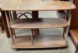 An Ercol bookcase of oval form with three tiers on casters