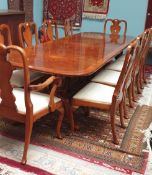 A Regency style walnut twin pedestal extending dining table and ten chairs,