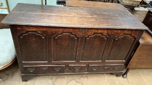 An 18th century oak coffer with a planked rectangular top above a four panelled front and base