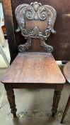 A Victorian mahogany hall chair with a carved shield shaped back above a solid seat on turned and