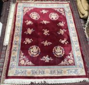 A Chinese rug with a red ground and multiple dragon roundels to a cream and red border,