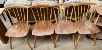 A set of four Ercol stick back dining chairs with solid seats on tapering legs