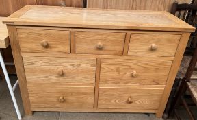 A modern ash chest with a rectangular top above an arrangement of seven drawers on square legs