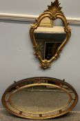A small gilt oval shaped wall mirror with leaf surmount together with a large oval wall mirror