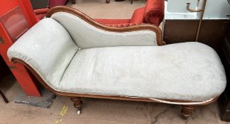 A Victorian walnut framed chaise longue on turned legs and casters