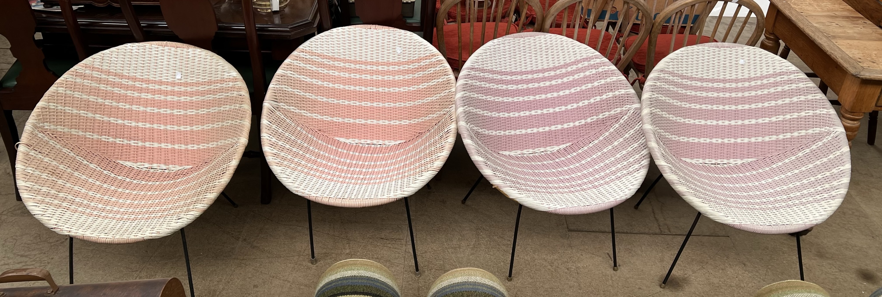 A set of four mid 20th century bucket chairs with woven plastic seats on a metal frame