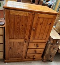 A pine low side cabinet with two cupboards and three drawers on a plinth