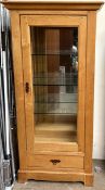 A modern oak display cabinet, with a moulded cornice above a glazed door and sides,