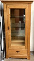 A modern oak display cabinet, with a moulded cornice above a glazed door and sides,