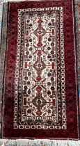 An Iranian Balouch wool rug with a cream ground and red multiple guard stripes 211 x 105cm