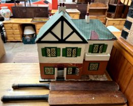 A mock tudor dolls house and furniture together with two cricket bats