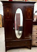An Edwardian mahogany wardrobe with a moulded cornice above a single mirror door and base drawer