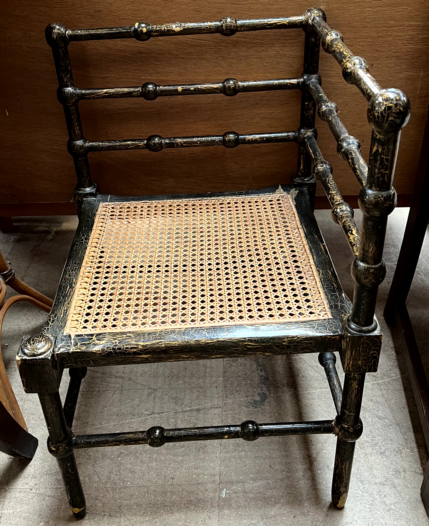 An Edwardian corner chair with ebonised and gilt decoration and bergere seat