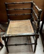 An Edwardian corner chair with ebonised and gilt decoration and bergere seat