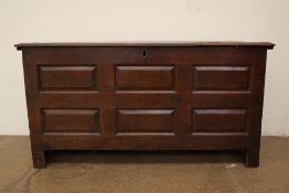 An 18th century oak coffer with a planked rectangular top above a six panelled front on stiles,