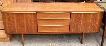 A mid 20th century teak sideboard with a pair of cupboards and three drawers on tapering legs